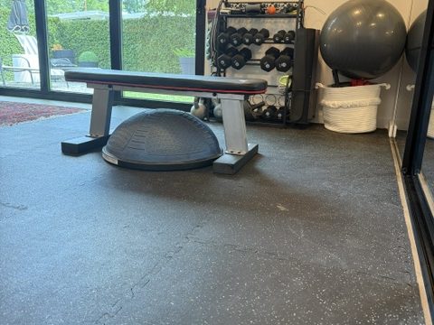 Compact training corner with a bench, stability ball, and wall rack beside a picture window