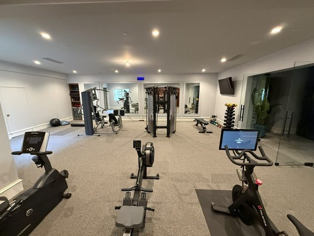 Cardio bank with rower, upright bike, and connected trainer facing the mirrors